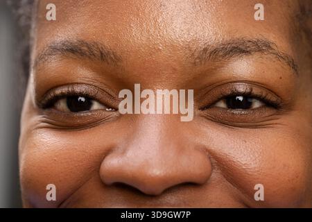 Afroamerikanische Frau zeigt Hautstruktur unter sanfter Beleuchtung im Studio auf grauem Hintergrund Stockfoto
