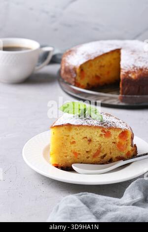 Stück hausgemachter Hüttenkäsekuchen mit getrockneten Aprikosen auf grauem Hintergrund Stockfoto