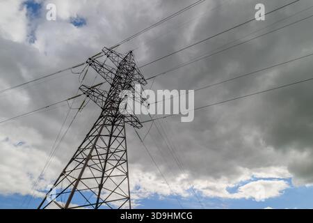 Ein beeindruckendes Bild von Stromleitungen vor einem bewölkten Himmel, das das Wesen der Energieinfrastruktur erfasst. Stockfoto