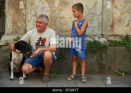 Vater und Sohn mit ihrem Hund auf der Straße in Pescia, Italien, interagieren, während eine Parade vorbei geht. Stockfoto