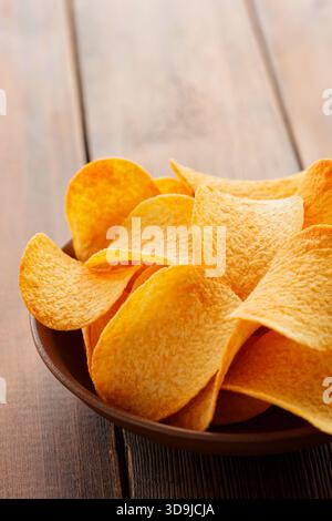 Goldene knusprige Kartoffelchips in Schüssel auf Holztisch Nahaufnahme Stockfoto