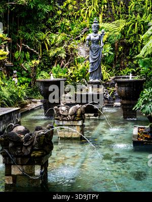 Ruhiger Garten mit Statue und Springbrunnen, umgeben von üppigem Grün. Stockfoto