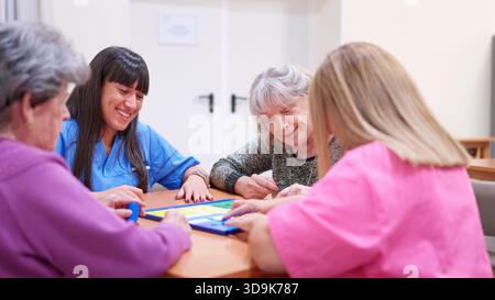 Pflegende und Senioren genießen gemeinsam das Brettspiel im Pflegeheim Stockfoto