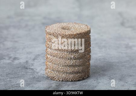 Schwammartiger synthetischer Metallschaum auf Beton. Nahansicht mit offenen Zellen und geriffelter Textur aus metallischem Schaumstoff. Metallic-Schaumstoff. Stockfoto