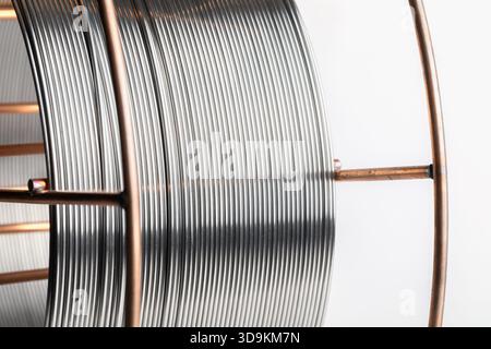 Nahaufnahme einer Rolle Metallschweißdraht. Eine Spule aus reflektierendem, glänzendem Metalldraht. Stockfoto