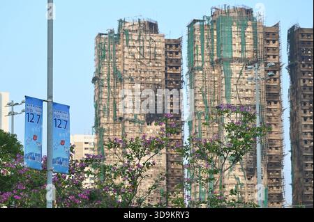 Hongkong, Hongkong. Dezember 2025. Eine Werbung für die Parlamentswahlen des Legislative Council 2025 und den Wohnkomplex des Wang Fuk Court in Tai Po nach einem tödlichen Brand am 6. Dezember 2025 in Hongkong. (Foto: Stringer/Nexpher Images/SIPA USA) Credit: SIPA USA/Alamy Live News Stockfoto