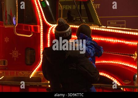 Ein Mann mit Kind in der Nähe eines Coca-Cola-Urlaubs-Trucks, Österreich, Wien, 12. Dezember 2024 Stockfoto