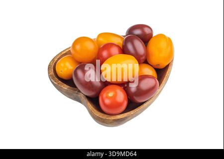 Farbenfrohe Mischung aus traditionellen Kirschtomaten in einer Holzschale, die über dem weißen Hintergrund geschossen wird und lebendige frische Produkte präsentiert Stockfoto