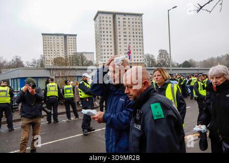 Falkirk, Schottland, Großbritannien. Dezember 2025. Mann, der von der Polizei weggeholfen wurde, nachdem er von einer Flasche getroffen wurde, die von einwanderungsfeindlichen Demonstranten geworfen wurde. Dies geschah, als sich Demonstranten vor dem Cladhan Hotel in Falkirk versammelten, um gegen die Unterbringung von Asylbewerbern an diesem Ort zu protestieren. Auf die Demonstration traf ein Gegenprotest, der von "Stand Up to Rassismus" organisiert wurde, dessen Unterstützer sich solidarisch mit den Migranten versammelten. Die Polizei war während der gesamten Zeit stark präsent, um Spannungen zu bewältigen und mögliche Zusammenstöße zwischen den beiden Gruppen zu verhindern. Quelle: Jacob Hughes/Alamy Live News Stockfoto