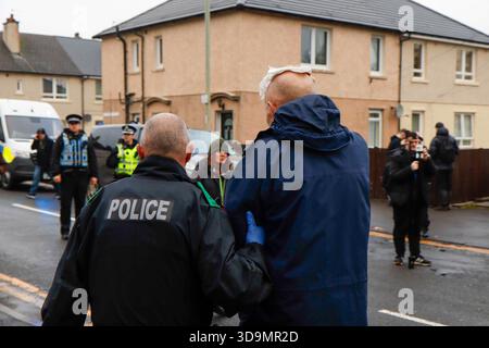 Falkirk, Schottland, Großbritannien. Dezember 2025. Mann, der von der Polizei weggeholfen wurde, nachdem er von einer Flasche getroffen wurde, die von einwanderungsfeindlichen Demonstranten geworfen wurde. Dies geschah, als sich Demonstranten vor dem Cladhan Hotel in Falkirk versammelten, um gegen die Unterbringung von Asylbewerbern an diesem Ort zu protestieren. Auf die Demonstration traf ein Gegenprotest, der von "Stand Up to Rassismus" organisiert wurde, dessen Unterstützer sich solidarisch mit den Migranten versammelten. Die Polizei war während der gesamten Zeit stark präsent, um Spannungen zu bewältigen und mögliche Zusammenstöße zwischen den beiden Gruppen zu verhindern. Quelle: Jacob Hughes/Alamy Live News Stockfoto