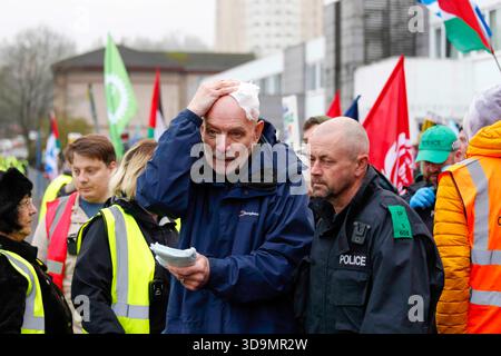 Falkirk, Schottland, Großbritannien. Dezember 2025. Mann, der von der Polizei weggeholfen wurde, nachdem er von einer Flasche getroffen wurde, die von einwanderungsfeindlichen Demonstranten geworfen wurde. Dies geschah, als sich Demonstranten vor dem Cladhan Hotel in Falkirk versammelten, um gegen die Unterbringung von Asylbewerbern an diesem Ort zu protestieren. Auf die Demonstration traf ein Gegenprotest, der von "Stand Up to Rassismus" organisiert wurde, dessen Unterstützer sich solidarisch mit den Migranten versammelten. Die Polizei war während der gesamten Zeit stark präsent, um Spannungen zu bewältigen und mögliche Zusammenstöße zwischen den beiden Gruppen zu verhindern. Quelle: Jacob Hughes/Alamy Live News Stockfoto