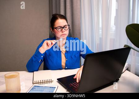 Remote-Analyse von Berichten durch Mitarbeiter während produktiver Arbeitstage im Home Office. Überprüfen von Diagrammen und Daten auf dem Laptop-Bildschirm während der konzentrierten Arbeitszeiten. Firma Stockfoto