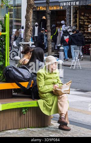Osaka, Japan - 31. März 2025: Sehr alte japanische Dame ruht auf einer Bank in den Straßen des America Mura District, dem bekannten Zentrum japanischer Jugendcu Stockfoto