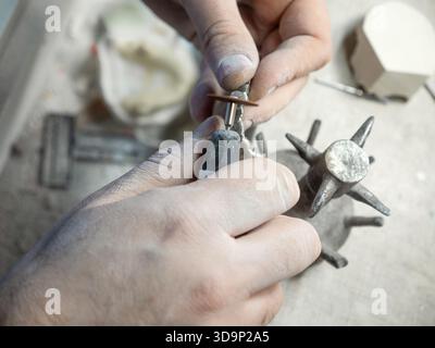 Zahntechniker mit Drehwerkzeug zum Schleifen von Metallkronen während des Herstellungsprozesses im Dentallabor, Nahaufnahme. Stockfoto