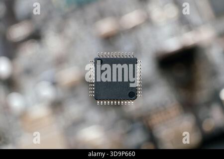 Isolierter ungelöteter Halbleiter-Mikrochip oder Mikrocontroller auf verschwommenem High-Tech-Hintergrund. Stockfoto