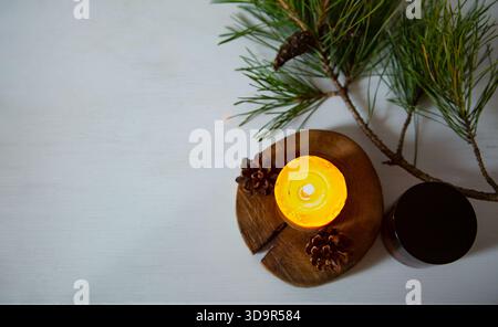 Brennendes Kerzenfeuer auf einem hölzernen Kerzenleuchter in der Nähe von grünem Tannenzweig. Großaufnahmehintergrund-Design-Konzept mit weißem leer Stockfoto
