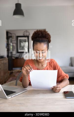 Glückliche junge Afroamerikanerin, die Papierdokumente liest Stockfoto