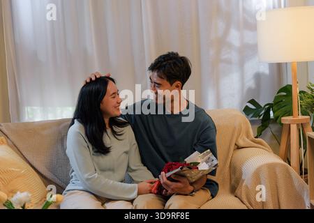 Glückliches junges Paar teilt zärtliche Liebe in gemütlichem Haus, Mann gibt Frau schönen romantischen valentinstag Stockfoto