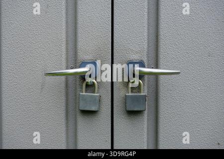 Zwei Metalltüren mit silbernen Griffen und Vorhängeschlössern, Nahansicht. Stockfoto