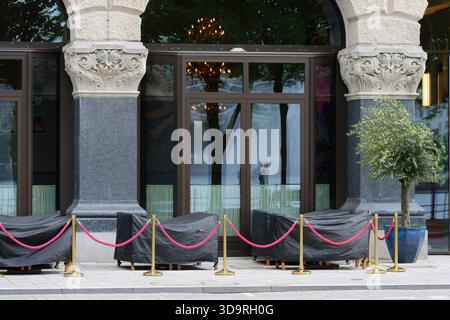 Ein elegantes historisches Gebäude am Hamburger Ballindamm mit geschnitzten Steinsäulen und großen Glastüren, davor sind rosa Seile zwischen Metallpfosten aufgereiht Stockfoto