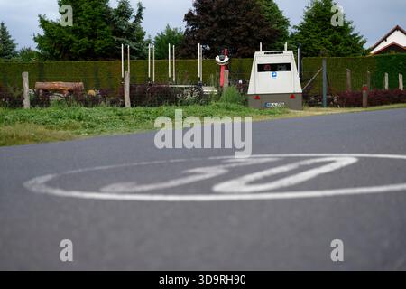 Eine lackierte Geschwindigkeitsbegrenzung von 30 km h in einem weißen Kreis ist auf der Fahrbahn sichtbar. Im Hintergrund befindet sich ein Anhänger mit Kennzeichen, Wohnwagen B Stockfoto