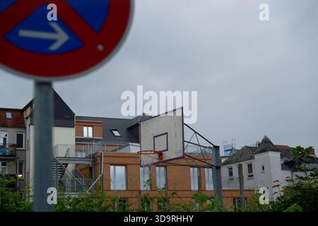 In der Nähe eines rostigen Basketballplatzes steht ein großes Schild ohne Parken. Im Hintergrund sind alte zwei- und dreistöckige Wohngebäude zu sehen. Stockfoto