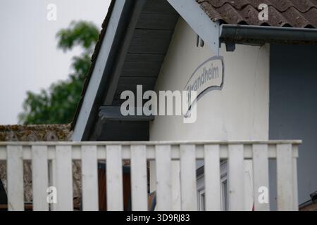 In einem weißen Haus mit einem Holzzaun in der Nähe befindet sich ein Schild über der Tür mit der Aufschrift Strandheim. Die Szene zeigt ein bezauberndes Äußere mit gepflegter Architektur Stockfoto