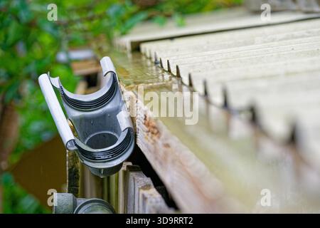 Entlang der Dachlinie ist das Abflusssystem auseinandergerissen, graue Kunststoffrohre sitzen nicht richtig ausgerichtet und die Gelenke stellen sich aus, Regenwasserspuren weisen auf Leckagen und eine Re hin Stockfoto