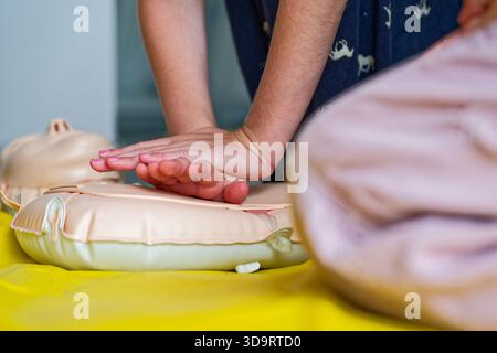 Nahaufnahme der Hände, die eine HLW-Thoraxkompressionen an einer Übungspuppe durchführen. Perfekt für Gesundheitserziehung, erste-Hilfe-Kurse, medizinische Ausbildung oder emer Stockfoto