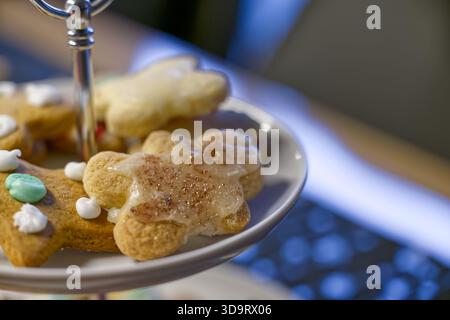 Eine Nahaufnahme eines Tellers dekorierter Lebkuchenkekse mit verschiedenen Formen und Glasur. Die Kekse sind auf einem mehrstufigen Ständer angeordnet, mit einem verschwommenen Stockfoto