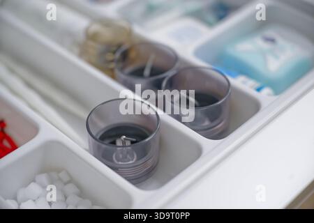 Eine Nahansicht eines Schubladen-Organizers mit verschiedenen Artikeln, darunter drei Glaskerzenständer, Zuckerwürfel und kleine Behälter mit Toilettenartikeln. Stockfoto
