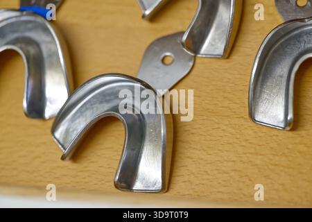 Nahaufnahme von Metallhaken auf einer Holzoberfläche, die ihr glänzendes, geschwungenes Design und ihre Befestigungslöcher zeigen. Stockfoto