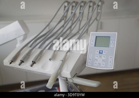 Eine Nahaufnahme eines Bedienfelds für Dentalstuhl mit mehreren Schläuchen und einer digitalen Anzeige in einer modernen Zahnklinik. Stockfoto