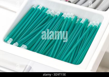 Nahaufnahme eines weißen Behälters, gefüllt mit blaugrünen Kunststoffröhrchen, ordentlich angeordnet und gestapelt. Stockfoto