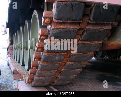 Nahaufnahme des Schienensystems eines Militärpanzers mit Metallgliedern und Rädern. Die Tankspur ist rostig und verschlissen, was auf eine starke Beanspruchung hinweist. Der bac Stockfoto