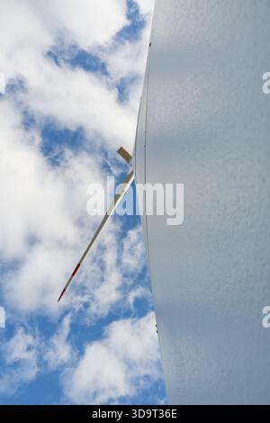 Eine Nahaufnahme eines Windenergieblatts vor einem Hintergrund von blauem Himmel und Wolken, die Struktur und Design der Windenergieanlage zeigt. Stockfoto