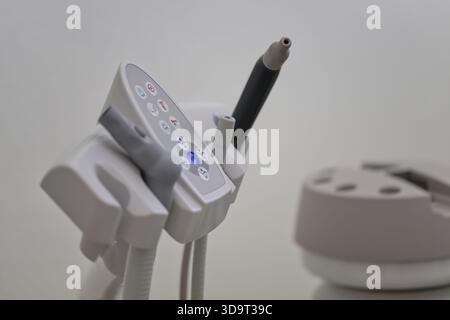Eine Nahaufnahme eines zahnärztlichen Werkzeugs mit Knöpfen und einem stiftähnlichen Instrument vor einem verschwommenen Hintergrund, was auf eine klinische Zahnumgebung hindeutet. Stockfoto