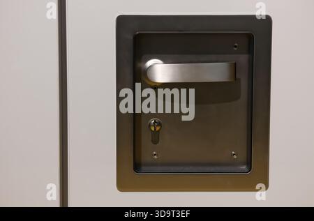 Nahaufnahme eines metallischen Türgriffs und eines Schlosses an einer weißen Tür. Stockfoto