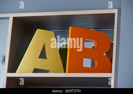 Farbenfrohe Holzbuchstaben A und B auf einem Regal mit modernem Design und sanfter Beleuchtung. Stockfoto