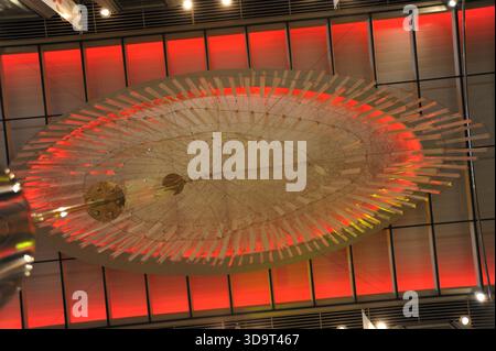 Atemberaubende Aussicht über eine große, künstlerische Installation mit kreisförmigem Design mit durchscheinenden Elementen, die in Rot- und Weißlicht beleuchtet ist Stockfoto