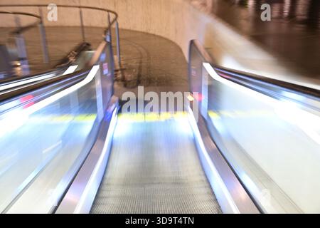 Ein verschwommenes Bild einer Rolltreppe, das die Bewegung und die dynamischen Lichteffekte zeigt. Die Rolltreppe scheint sich in einer modernen, möglicherweise städtischen Umgebung zu befinden Stockfoto