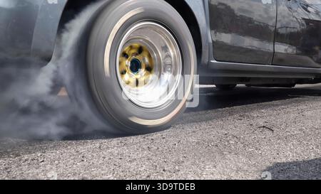 Ziehen Sie den brennenden Reifen des Rennwagens an der Startlinie auf der Rennstrecke Stockfoto