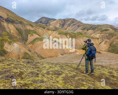 Wanderer fotografieren die riesigen, farbenfrohen Rhyolith-Berge und den silbrigen Talboden im isländischen Hochland. Stockfoto