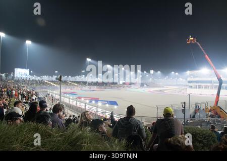 Die Zuschauer beobachten den Großen Preis von Katar auf der Rennstrecke unter hellem Licht, während sich die Autos auf die nächtliche Rennstrecke im Jahr 2025 vorbereiten. Stockfoto