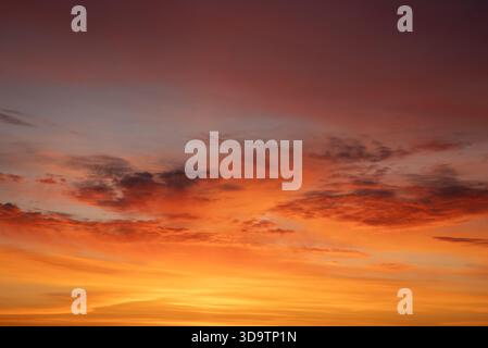 Der Abendhimmel ist mit leuchtenden Wolken in den Farben Orange, Rot und Violett gemalt, eine ruhige, malerische Wolkenlandschaft in der Abenddämmerung, die warmes, ruhiges atmosphärisches Licht einfängt Stockfoto