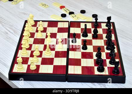 Auf dem Schreibtisch ist ein Schachbrett mit schwarz-weißen Stücken angeordnet. Stockfoto