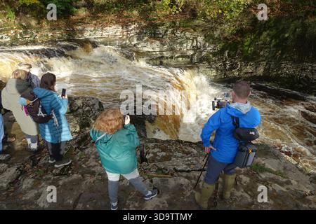 Menschen, die Lachssprünge im River Ribble bei den Stainforth Force Waterfalls in Ribblesdale in den Yorkshire Dales, England, beobachten Stockfoto