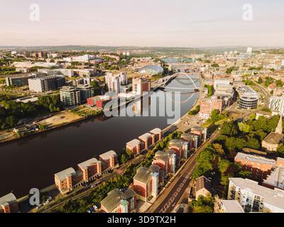 Newcastle upon Tyne: 9. August 2025: Gebäude säumen die Newcastle Quayside bei Sonnenaufgang. Brücken stehen über dem Fluss und spiegeln sich im Wasser darunter. Dro Stockfoto
