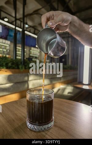 Frischer Kaffee wird in den Glasbecher im Cafe gegossen Stockfoto