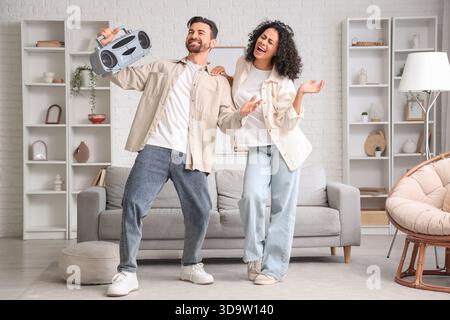 Junges Paar mit Boombox, das zu Hause Radio hört Stockfoto